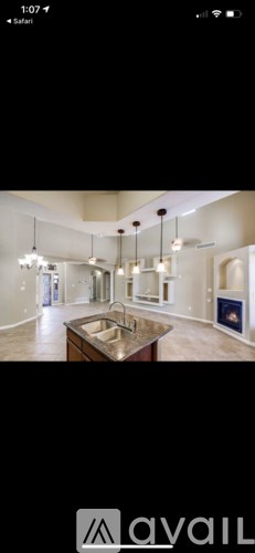 A modern kitchen with a central island and pendant lights.