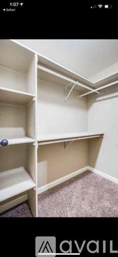 A room with a carpeted floor and white shelving units.