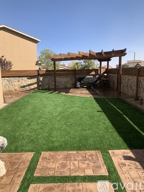 A backyard with a green lawn and a stone border.