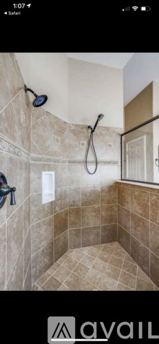 A tiled bathroom with a shower head and a handheld shower.