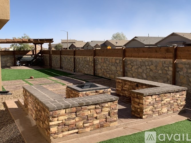 A backyard with a stone wall and a green lawn.