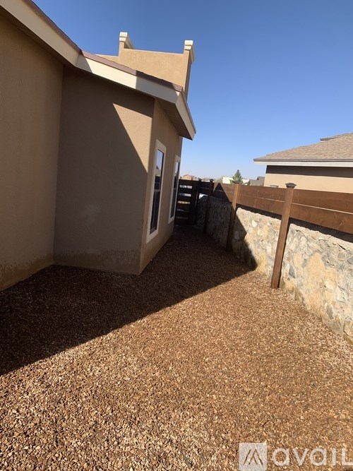 A house with a brown gravel driveway and a wooden fence.