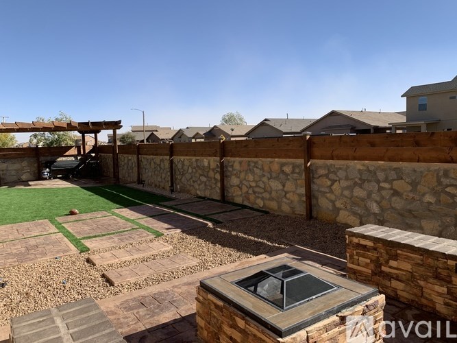 A backyard with a stone wall and a small patio.