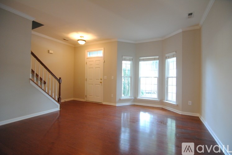 A large empty room with wood floors and a staircase.