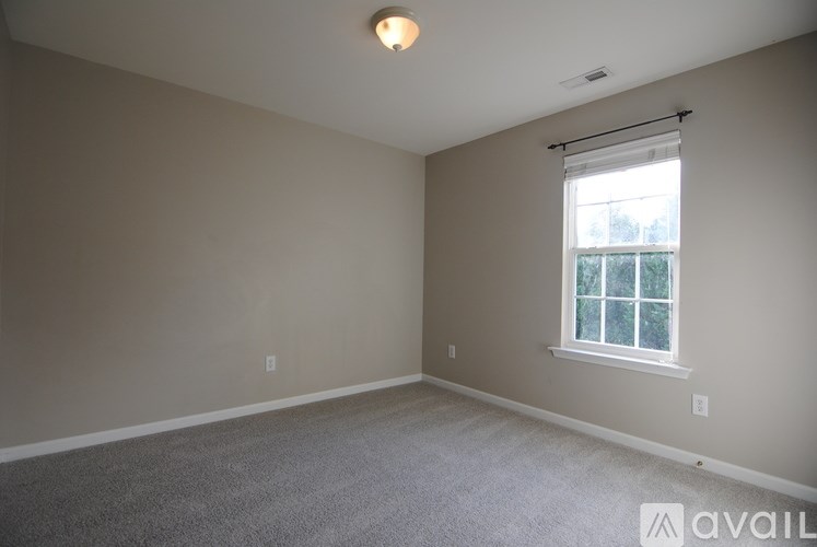 A room with a window and a carpeted floor.