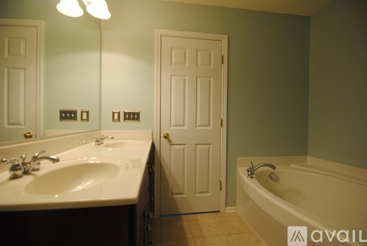 A bathroom with a tub, sink and mirror.