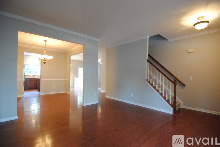 A spacious room with wooden floors and a staircase.