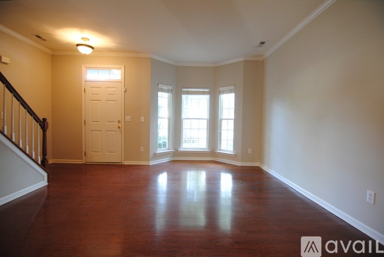 A room with wooden floors and a staircase on the left side.