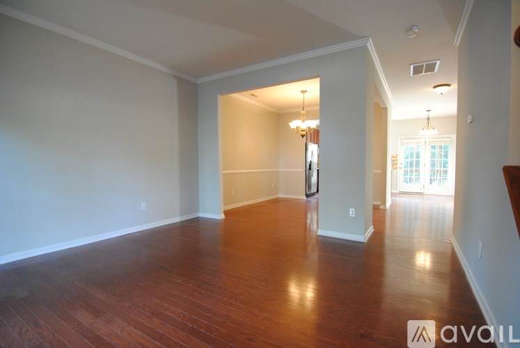 A spacious room with wooden floors and a large window.