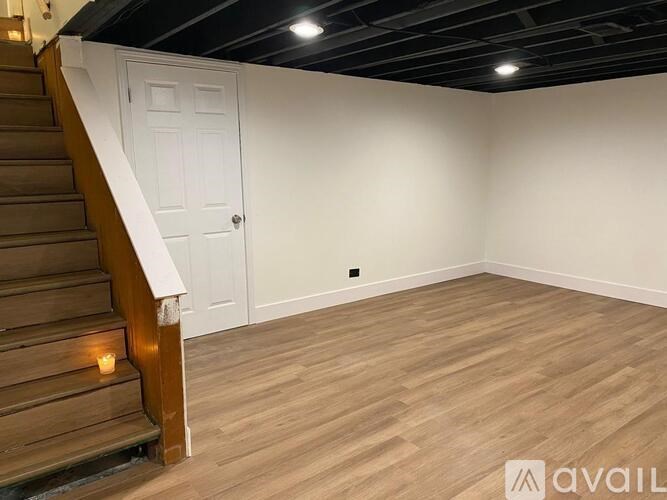 A room with wooden flooring and a staircase with a lit candle on the steps.