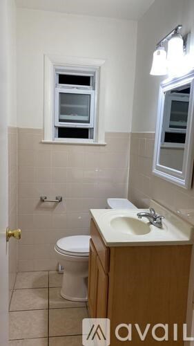 A bathroom with a toilet, sink, and window.