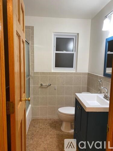 A bathroom with a toilet, sink, and a window.