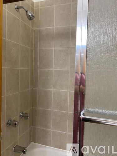 A bathroom with a tiled shower and a glass door.