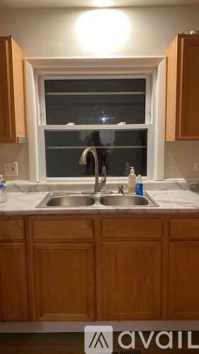 A kitchen with wooden cabinets and a window above the sink.