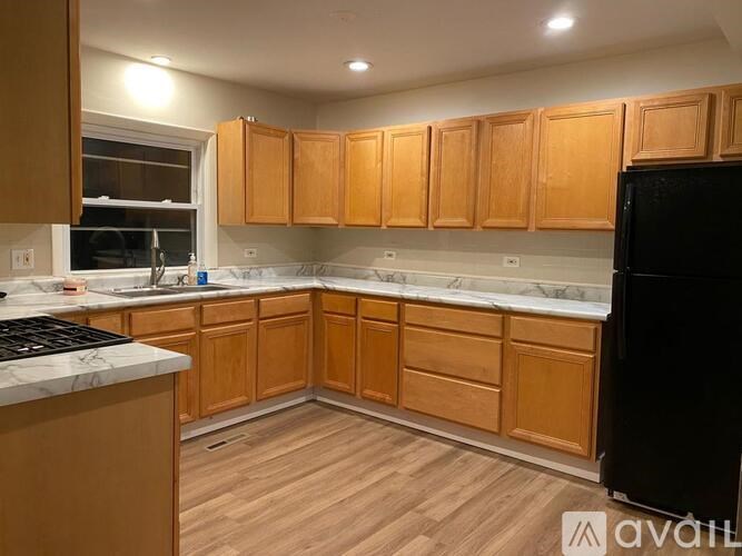 A kitchen with wooden cabinets and a black refrigerator.