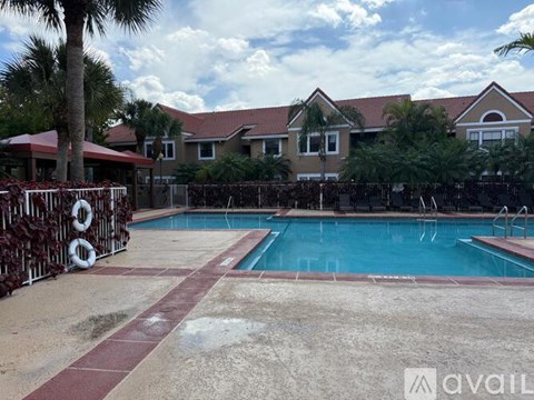A pool surrounded by a fence and a house in the background.