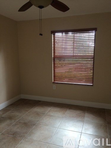A room with a ceiling fan and a window with blinds.