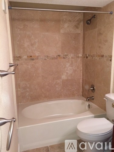 A bathroom with a tub, toilet and shower.