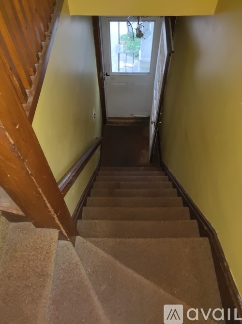 A staircase with a wooden handrail and beige carpeted steps.