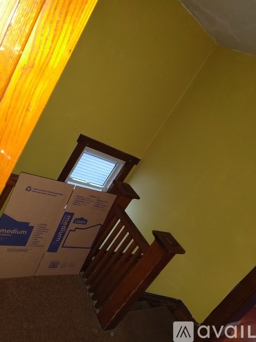 A cardboard box with blue writing on it sits on a carpeted floor.