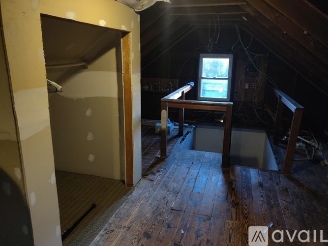 A room with wooden floors and a window with a view of trees outside.