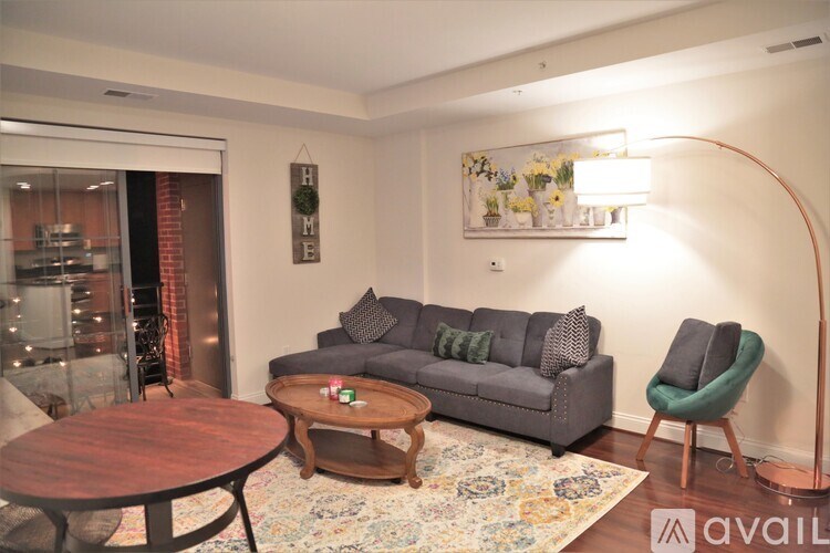 A living room with a grey couch, a wooden coffee table, and a green armchair.