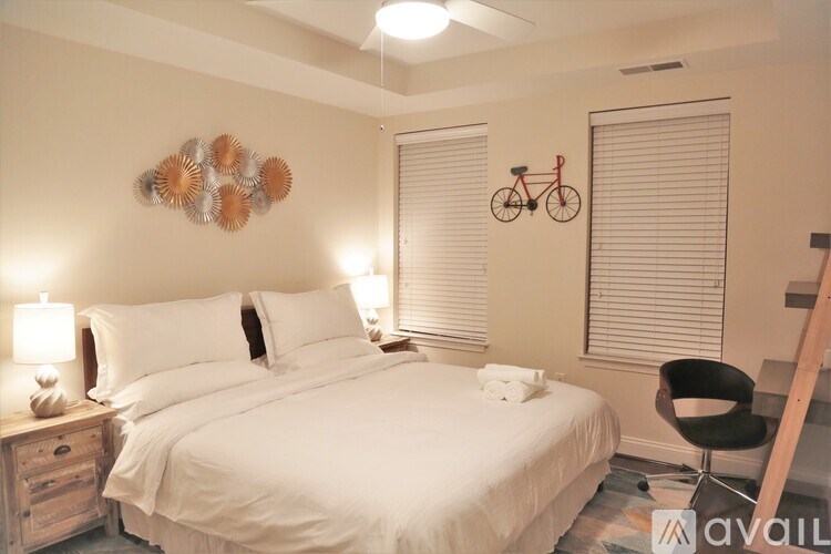 A bedroom with a large bed, a chair, and a bicycle decoration on the wall.