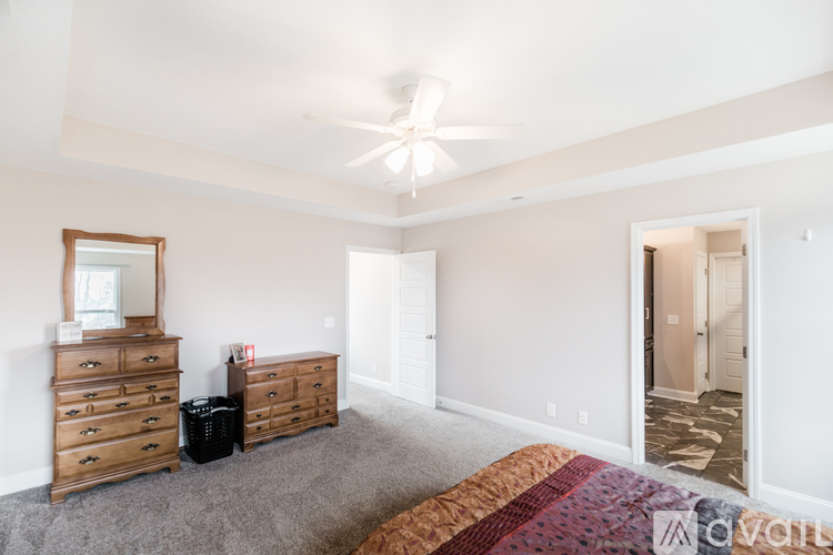 A bedroom with a bed, dresser, mirror, and a ceiling fan.