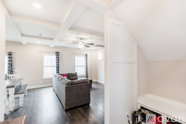 A spacious living room with a grey couch and a white ceiling fan.