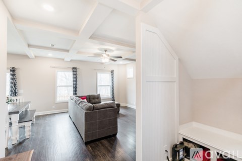 A spacious living room with a grey couch and a white ceiling fan.