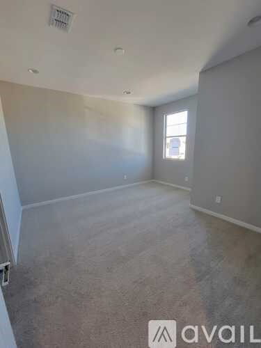 A room with a window and a carpeted floor.