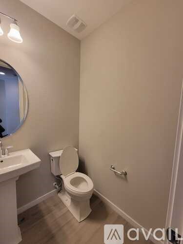 A bathroom with a toilet, sink, and mirror.