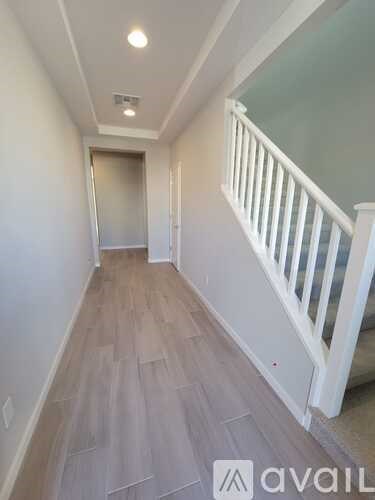A hallway with wooden floors and white railings.