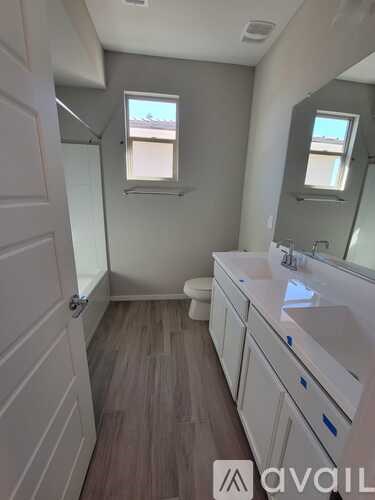 A bathroom with a toilet, sink, and mirror.