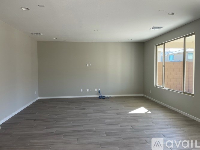 A room with a wooden floor and a window on the right side.