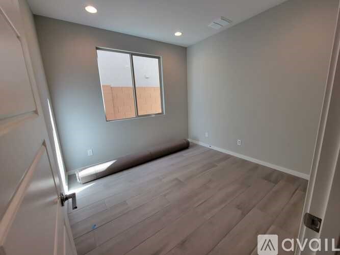A room with a window and wooden flooring is available for rent.