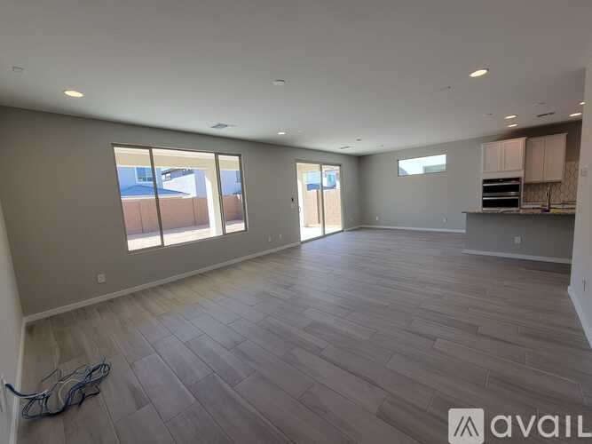 A spacious room with wooden flooring and large windows.