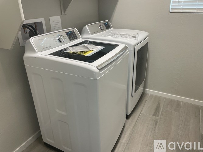 A white washing machine with a black control panel is in a room with light grey walls.