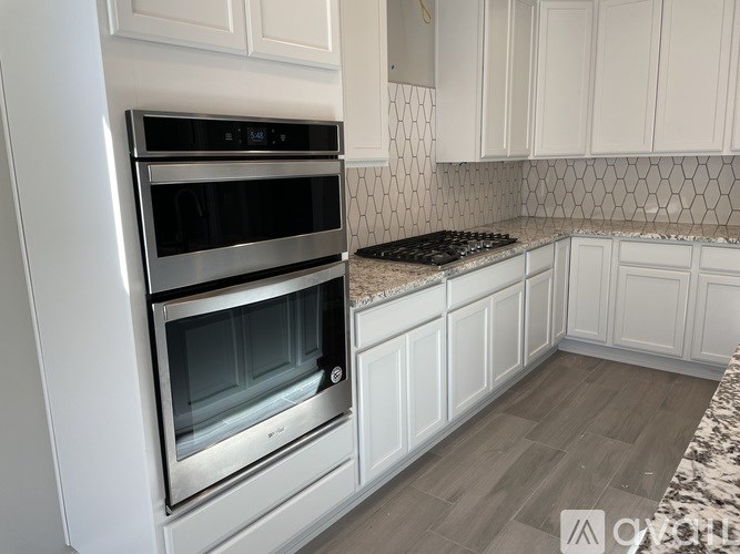A modern kitchen with a double oven and white cabinets.