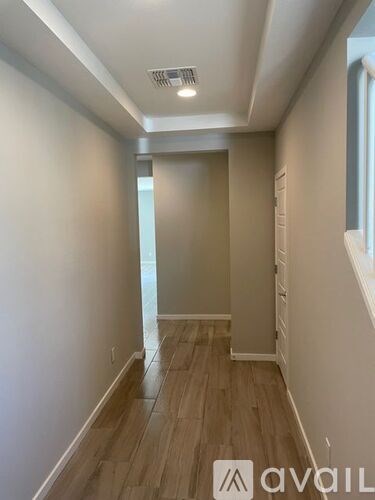 A hallway with wooden floors and white walls.