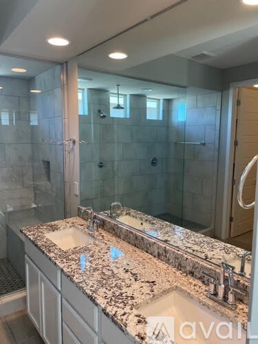 A bathroom with a granite countertop and a walk-in shower.