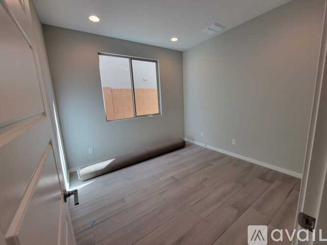 A room with wooden flooring and a window with a white frame.