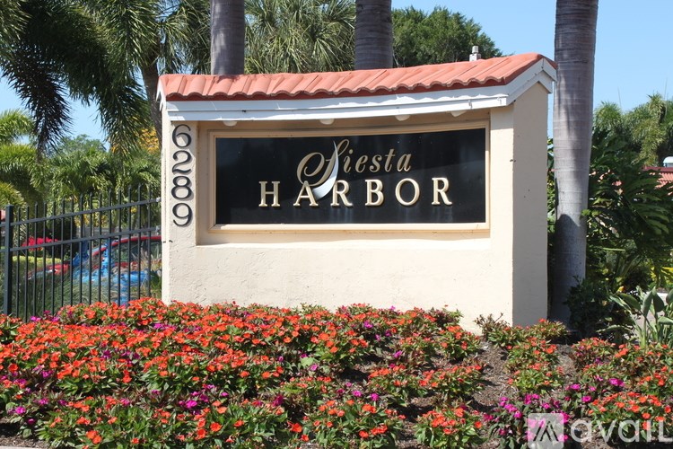 A sign that says "Oyster Harbor" in front of some flowers.
