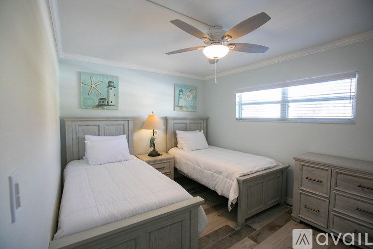 A bedroom with two beds, a ceiling fan, and a window.