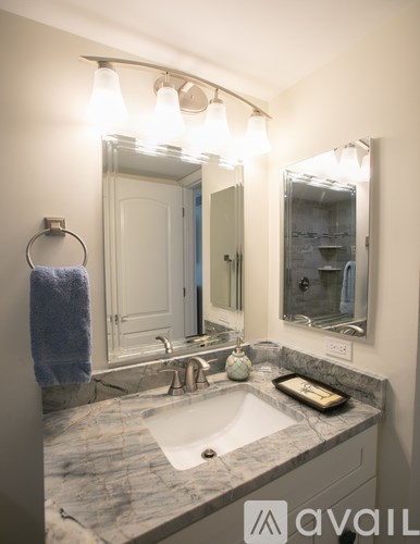 A bathroom with a marble counter top and a large mirror above the sink.