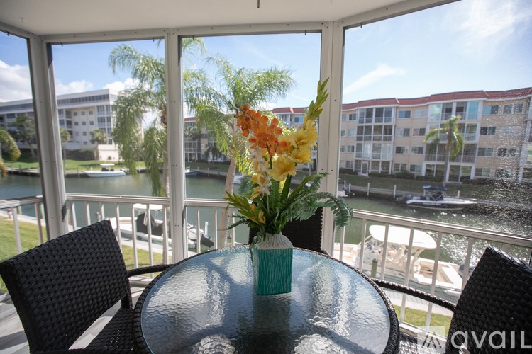 A table with a vase of flowers on it in front of a balcony.