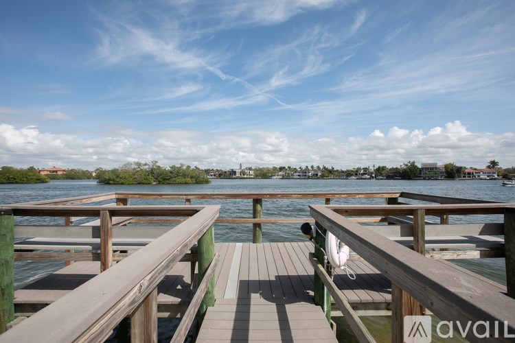 A wooden dock extends into a calm body of water with a clear blue sky above.