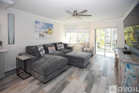 A living room with a grey couch and a ceiling fan.