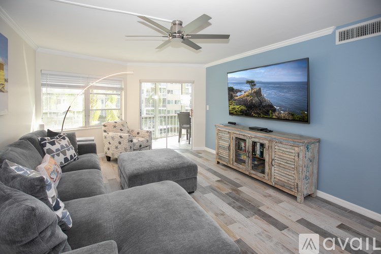 A living room with a grey couch and a television on a wooden stand.