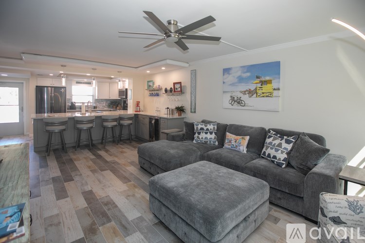 A living room with a grey couch and a fan on the ceiling.